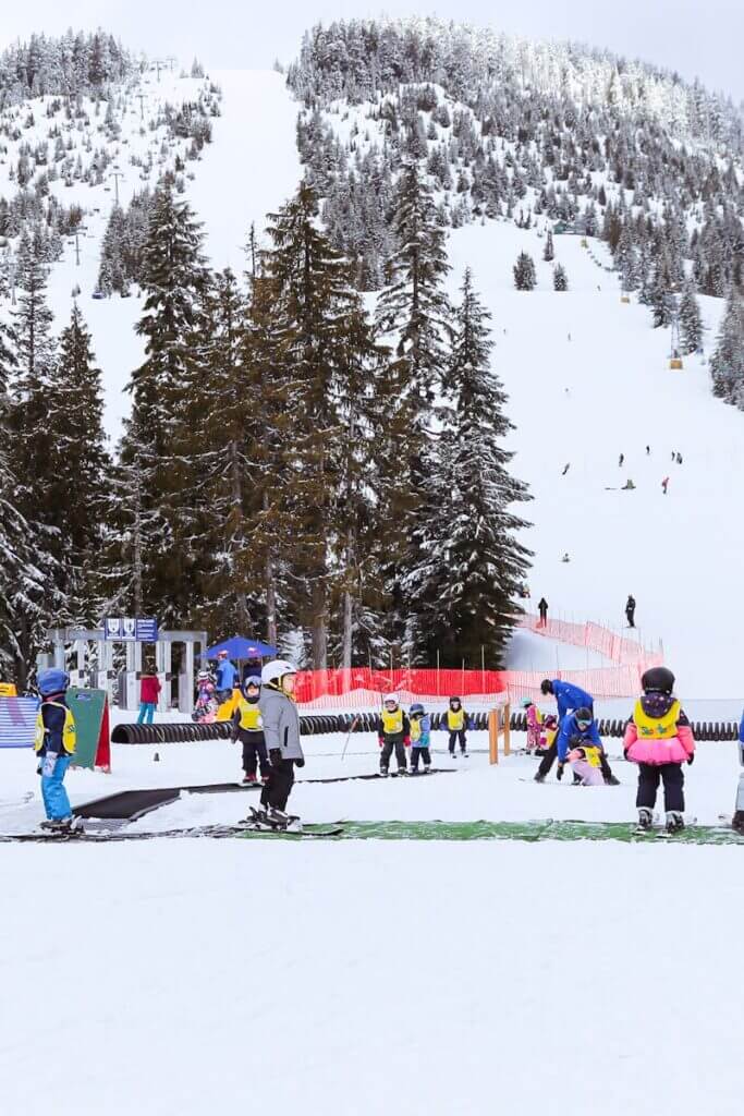 Children learning to ski during a winter lesson at a snow-covered mountain resort.